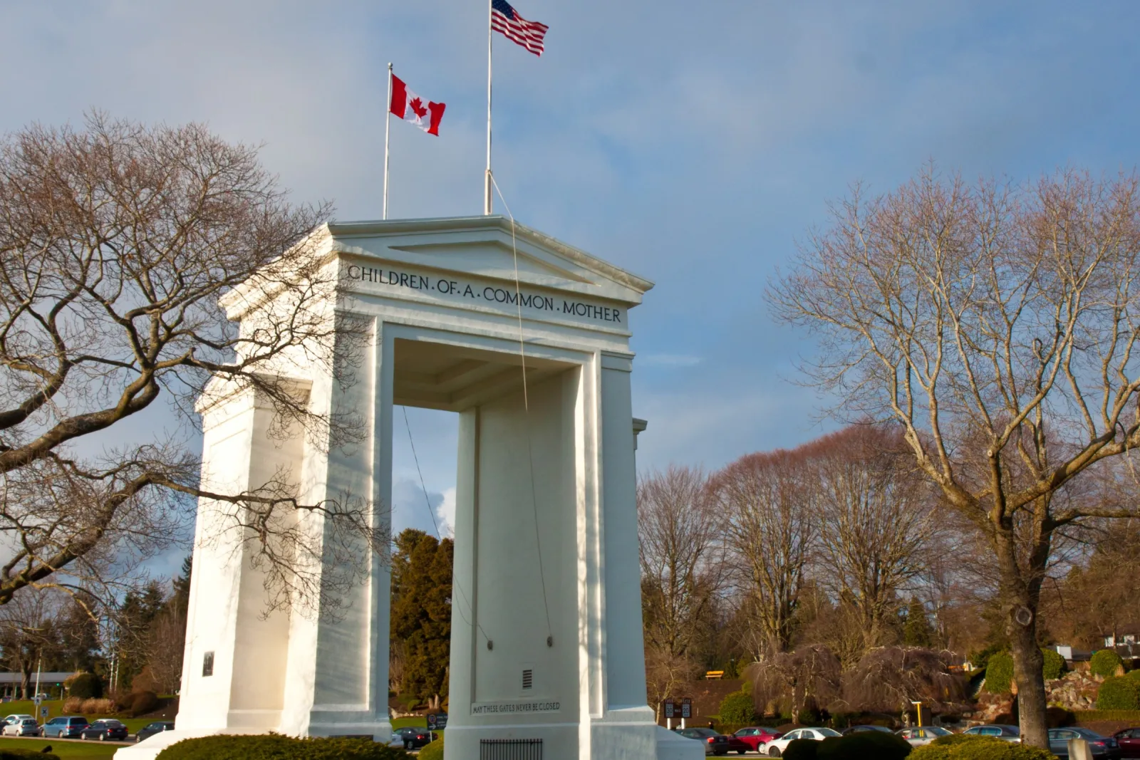The white Peace Arch monument flying US and Canadian flags, in Peace Arch Historical State Park